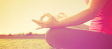 hands of a woman meditating in a yoga pose on the grass toned w